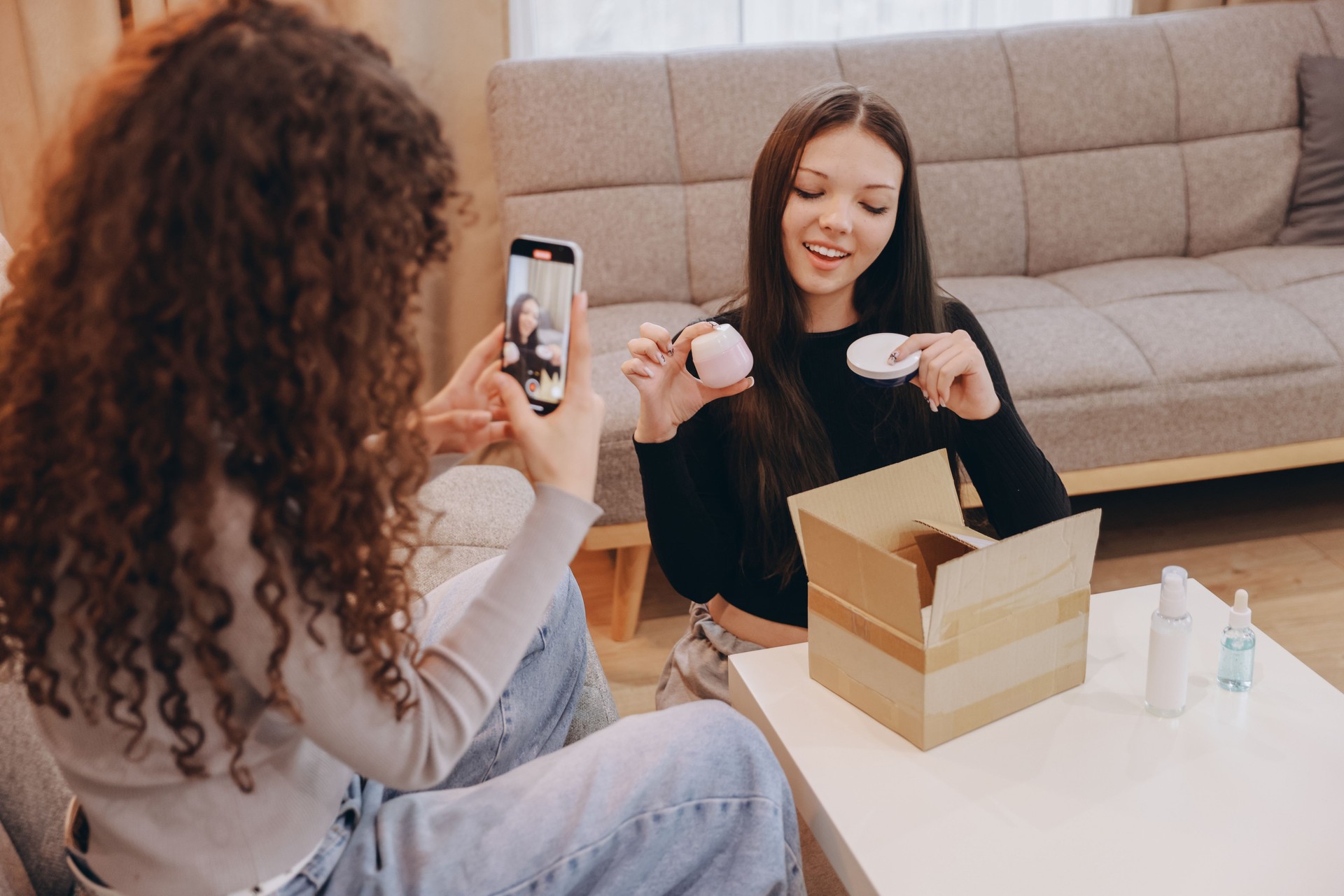 Teenager filming her friend unboxing beauty products for social media