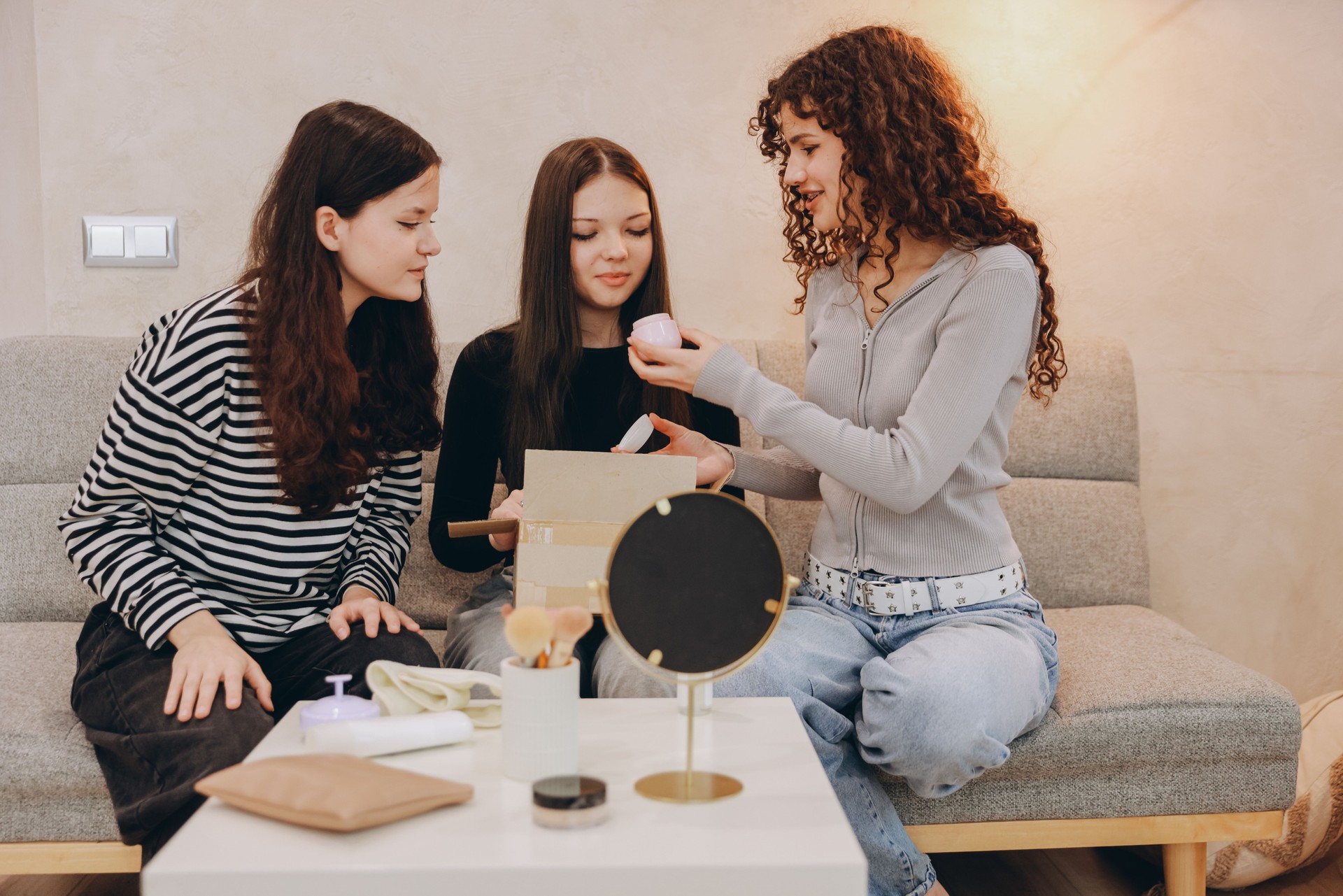 Teenage girls testing beauty products from delivery box at home